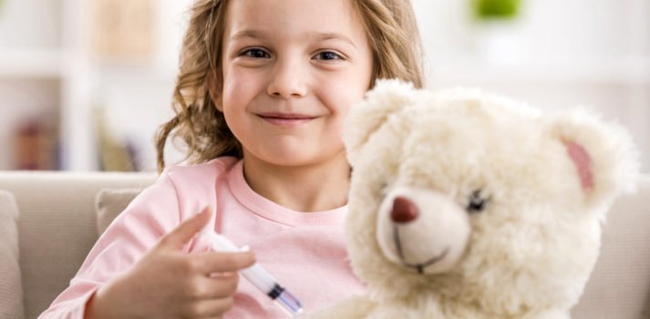 kleines Mädchen impft ihren Teddy mit Spielzeugspritze