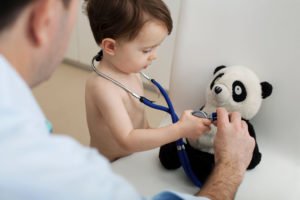 kleiner Junge hält Stethoskop an sein Panda-Kuscheltier