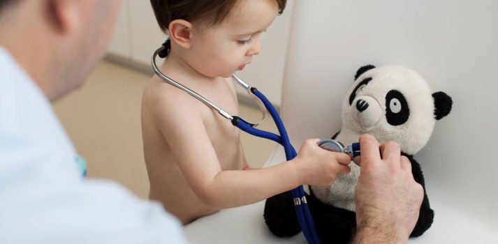 kleiner Junge hält Stethoskop an sein Panda-Kuscheltier