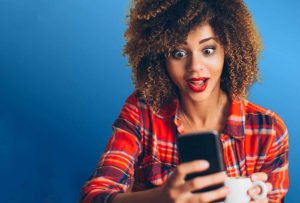 Frau sieht erstaunt auf ihr Smartphone