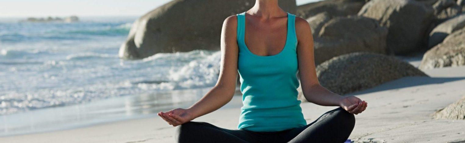 Frau macht Yogaübungen am Strand