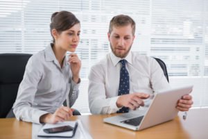 Mann in Businessoutfit erklärt Frau etwas am Laptop