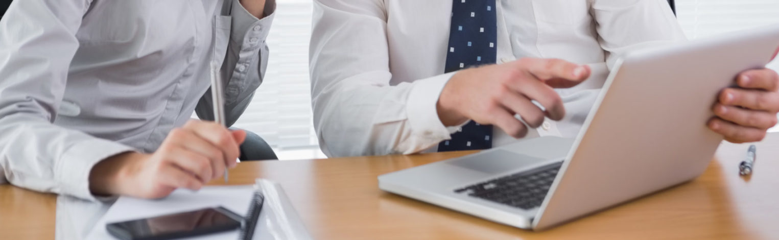 Mann in Businessoutfit erklärt Frau etwas am Laptop