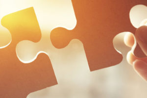 Hände die Puzzelteile halten