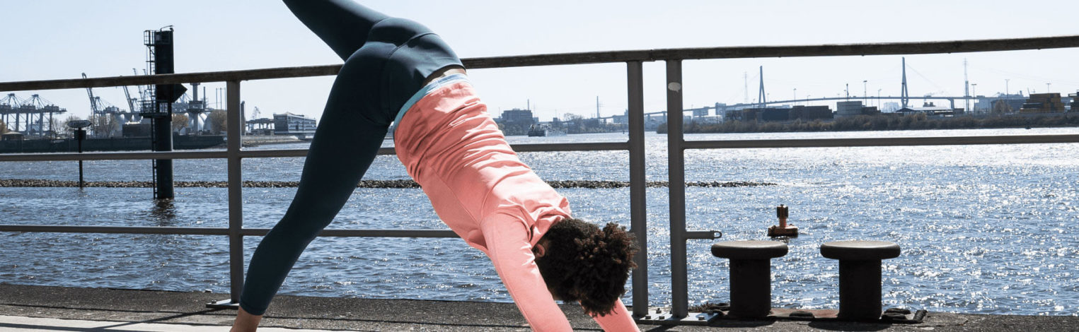 Frau macht Yogaübungen am Wasser