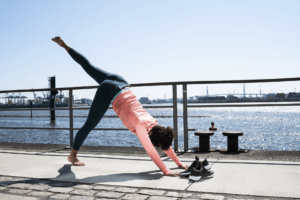 Frau macht Yogaübungen am Wasser