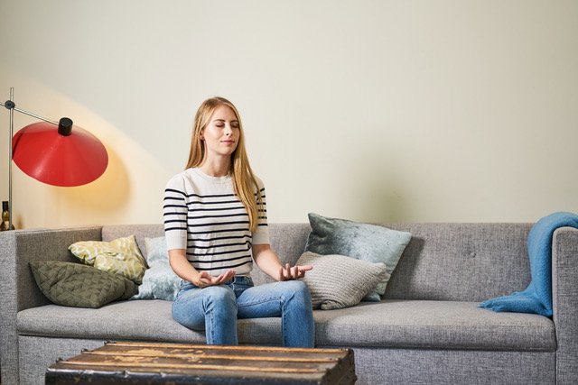 Frau meditiert auf Sofa